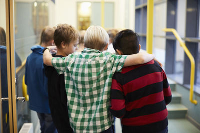 Boys standing arm around in school corridor