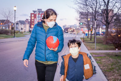 Mom and her son coming back from outdoor playground carrying a football