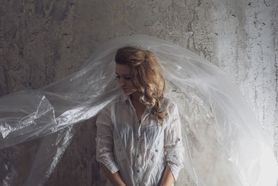 Woman with plastic against wall