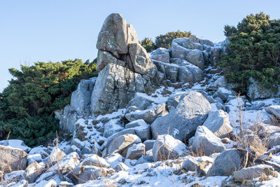 Stone wall by rocks against clear sky