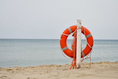 View of life buoy post on beach against sky