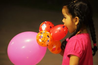 Side view of girl holding balloons