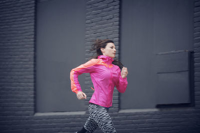 Sportswoman running against building