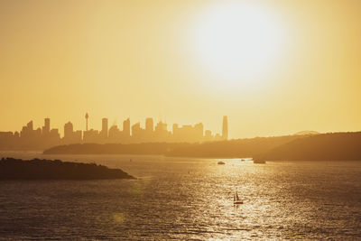 Scenic view of sea by buildings against sky during sunset