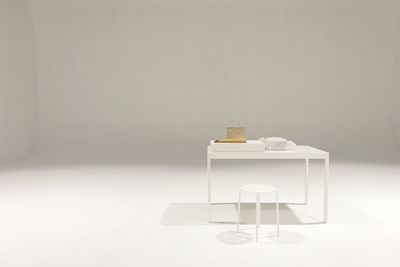 Stool by table against white background