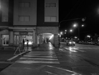 Illuminated street amidst buildings in city at night