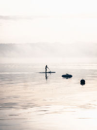 Silhouette person in sea against sky