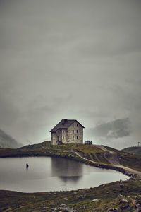 Building by lake against sky