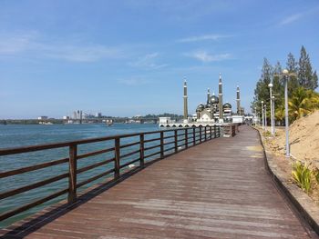 Footpath by sea against sky in city