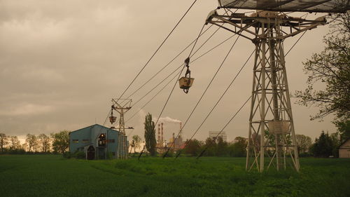 Electricity pylon on field against sky