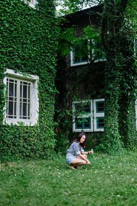 Woman sitting on grass against building