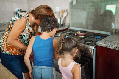 Grandmother teaching the kids how to cook looking at the meal in the oven