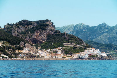 Scenic view of sea by townscape against clear sky