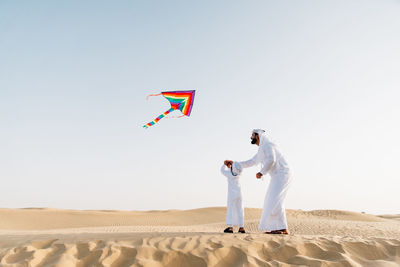 Men standing on desert against clear sky