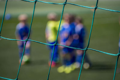 Soccer players seen through chainlink fence