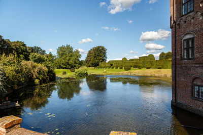 Building by pond against sky