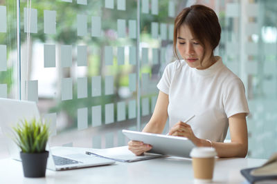 Woman using mobile phone while sitting on table