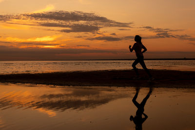 Silhouette man walking at beach during sunset