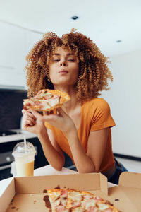 Portrait of smiling young woman having food at home