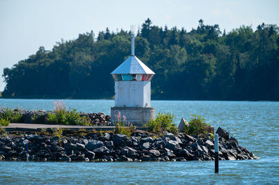 A small lighthouse standing on top of a breakwater made out of rocks and stones.