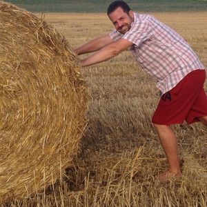 Man pushing hay bale