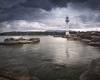 Lighthouse by sea against sky