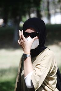 Portrait of young woman wearing sunglasses standing outdoors