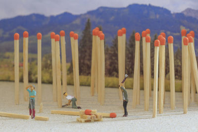 Close-up of figurines with matchsticks on sand