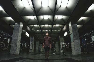 Man looking up while standing at illuminated parking lot
