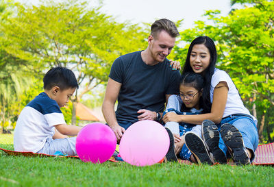 Happy family resting on grassy field at park