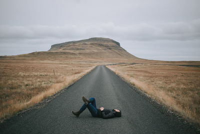 Low section of man on road against sky