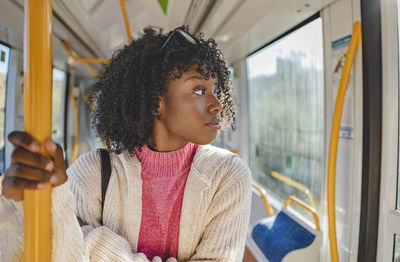 Young woman with curly hair standing in tram