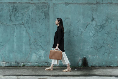 Side view of woman standing against wall