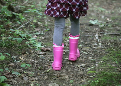 Low section of girl wearing rubber boots walking on field