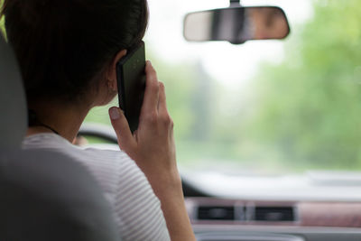 Rear view of mature woman using mobile phone while sitting in car