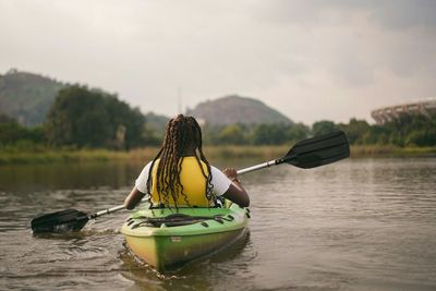 Rear view of man on boat in lake against sky