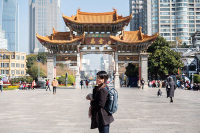 Portrait of woman with backpack standing in city