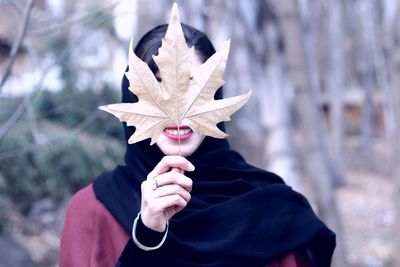 Midsection of woman holding autumn leaf