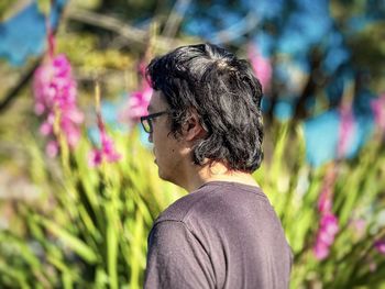 Side view of young woman standing amidst plants