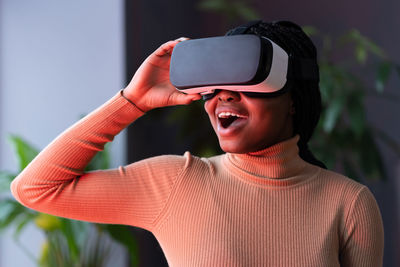 Impressed black woman sitting in neon light with drop jaw wearing virtual reality headset