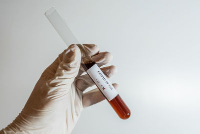 Close-up of hand holding bottle against white background
