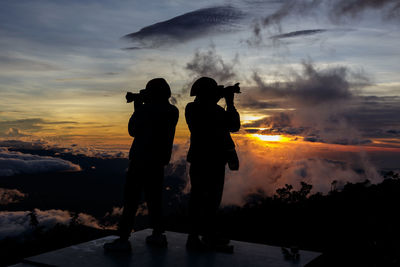 Silhouette people standing against sky during sunset