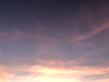 Low angle view of vapor trails in sky during sunset