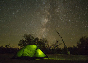 Illuminated tent on field against sky at night 