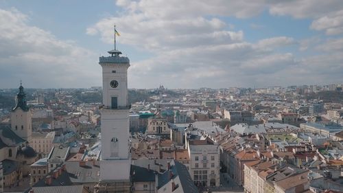 Aerial view of buildings in city against cloudy sky