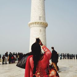 Low angle view of woman photographing historic monument against sky