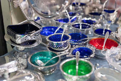 Silverwar- small silver vessels with teaspoon colored in blue, green and red.