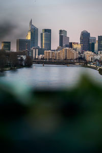 River by buildings in city against sky at dusk