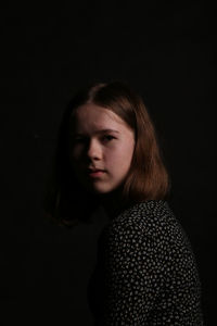 Young woman standing against black background