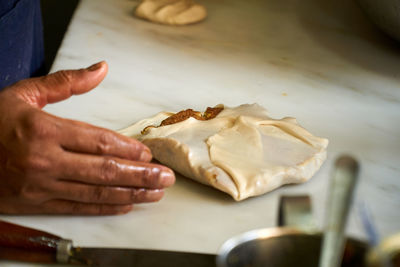 Midsection of person preparing murtabak in kitchen